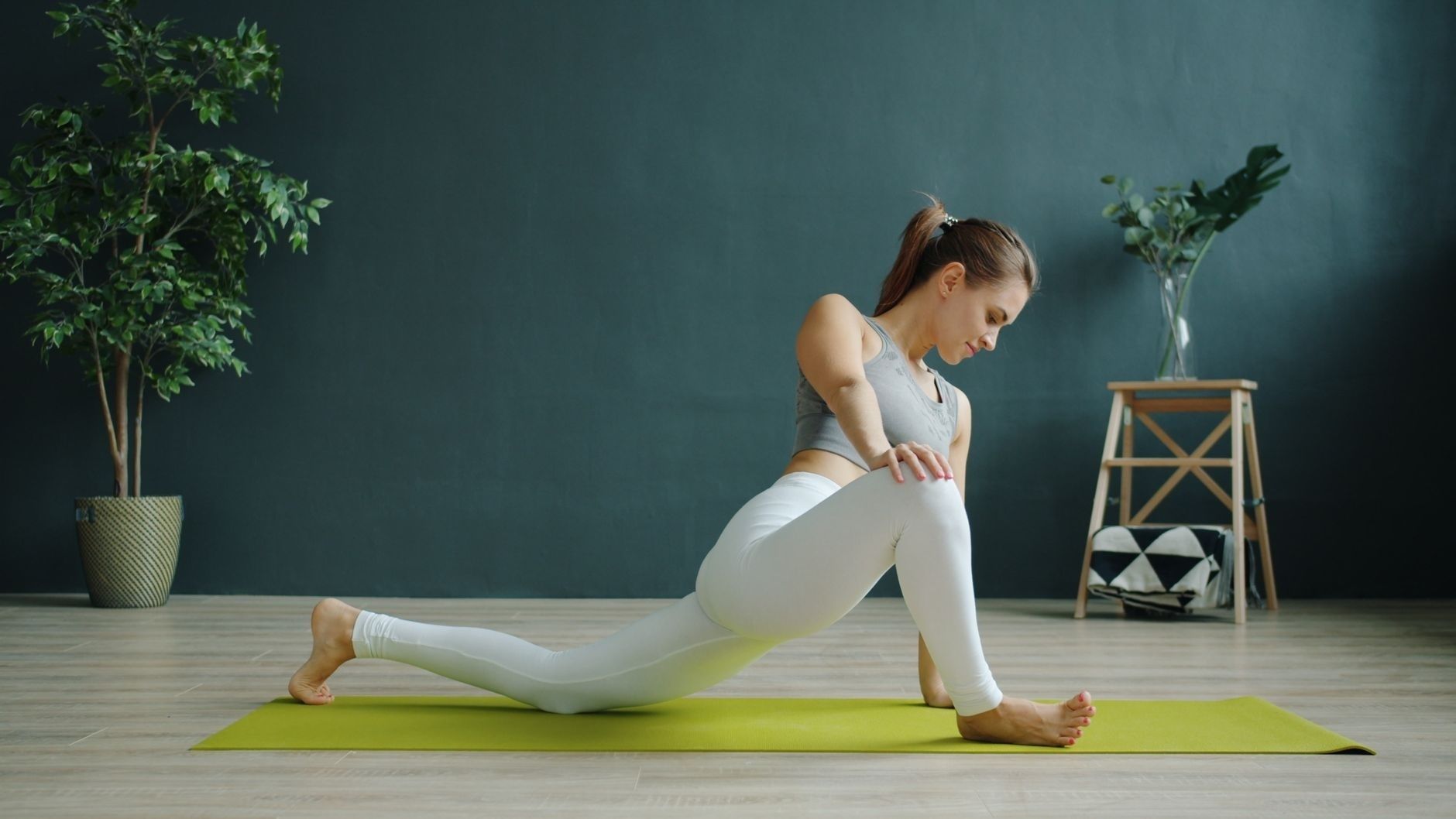 Frau übt eine tiefe Hüftdehnung im Ausfallschritt auf einer Yogamatte